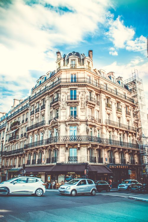 Free Stunning view of a classic Parisian building on a busy city street corner, capturing urban vitality. Stock Photo