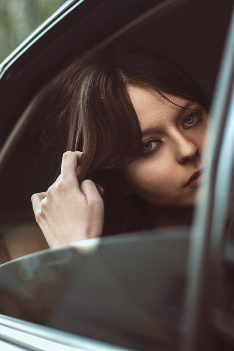 A Woman Fixing Her Hair In A Car