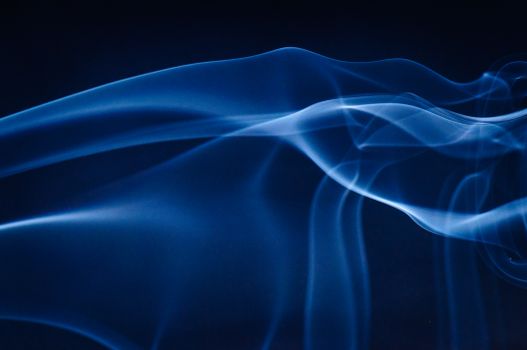 Artistic abstract image of blue smoke on a dark background, creating a mesmerizing wave pattern.