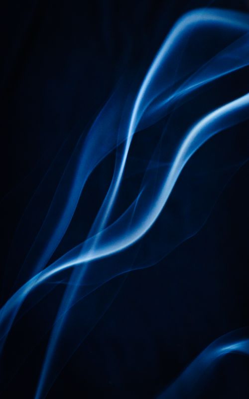 Free Close-up of abstract blue smoke swirls against a dark background, creating an illuminated and mysterious atmosphere. Stock Photo