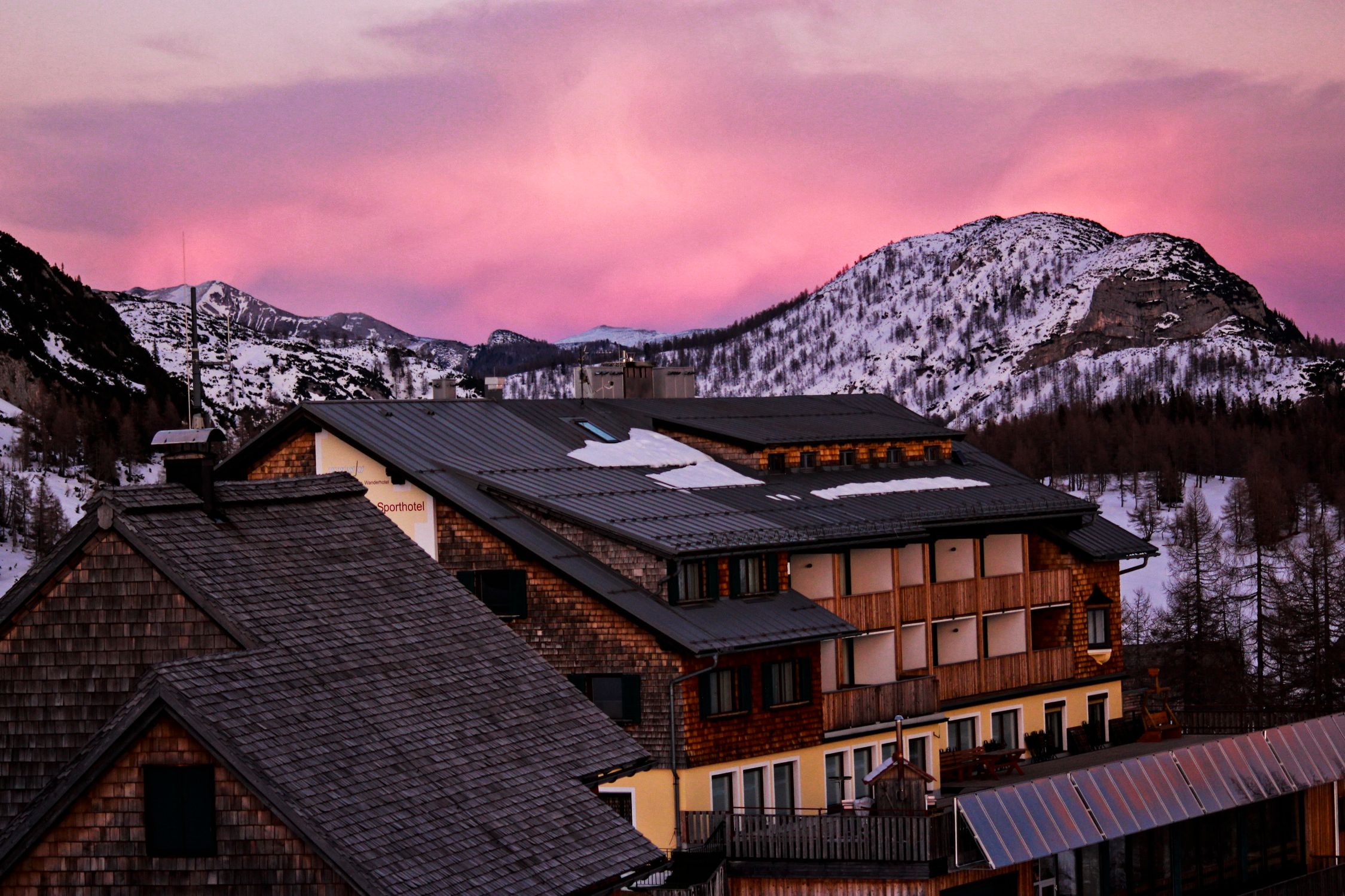 Beautiful mountain lodge with snow and pink sky at dusk, creating a serene winter scene.