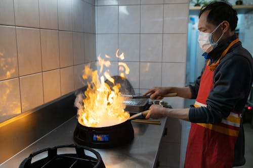 A Man Cooking While Wearing a Face Mask