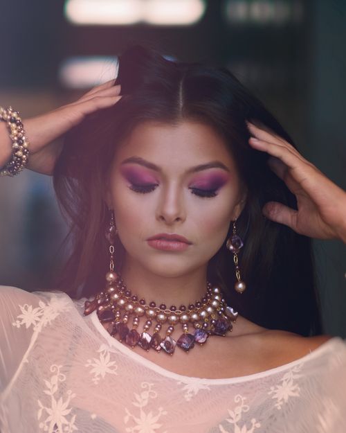 Free Close-up portrait of a woman with elaborate makeup and jewelry, eyes closed, exuding elegance. Stock Photo