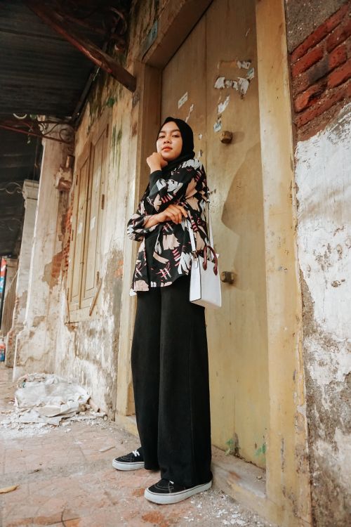 Free A woman in trendy streetwear poses confidently on a Cirebon street, showcasing urban Indonesian fashion. Stock Photo