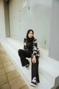 Woman in Black and White Hijab Sitting on White Floor Tiles