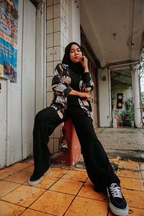 Free Fashionable woman in hijab poses confidently outdoors in urban Indonesia. Stock Photo