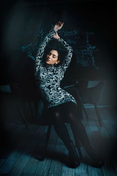 Fashionable woman sitting with arms raised in a stylish studio shoot.