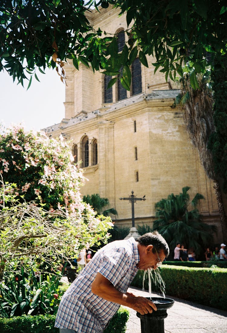 A Man Drinking On A Water Fountain