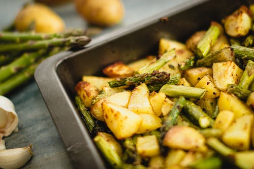 A Close-Up Shot of Cooked Potatoes and Asparagus on a Metal Tray