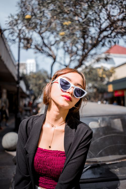 Free Elegant woman in sunglasses posing fashionably outdoors in urban setting. Stock Photo