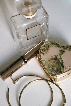 Artistic arrangement of perfume, lipstick, and jewelry on a soft background.