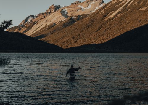 Free A person fly fishing in a scenic mountain lake during sunset, perfect for leisure and outdoor enthusiasts. Stock Photo