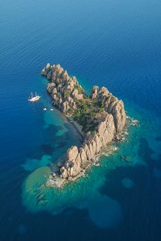 A breathtaking birds-eye view of a remote rocky island surrounded by clear blue ocean.