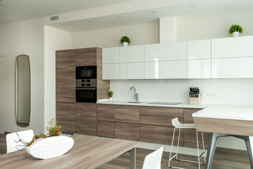 Free Built in ovens and stove in contemporary kitchen with minimalist wooden furniture and dining area in daylight Stock Photo