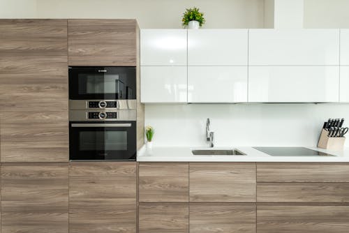 Free Interior of modern kitchen with white and wooden minimalist cabinets and built in appliances in apartment Stock Photo