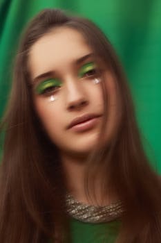 Creative portrait of a woman with bold green makeup and a unique artistic vibe, styled in a green background.