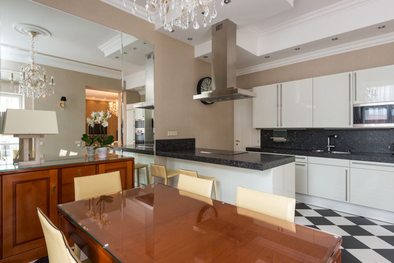 Modern kitchen with marble counter and dining table on glossy tiles