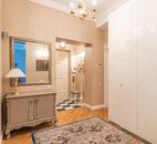 Door at entry of flat made in vintage style with glowing lamp and chandelier hanging on ceiling near glossy closet