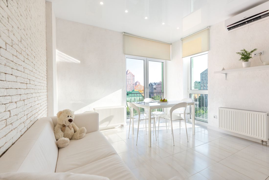 Interior of white kitchen furnished with sofa and chairs and table near windows