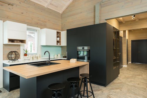 Minimalist style of kitchen with bar chairs at counter and matte cupboards in spacious private house