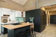 Minimalist style of kitchen with bar chairs at counter and matte cupboards in spacious private house