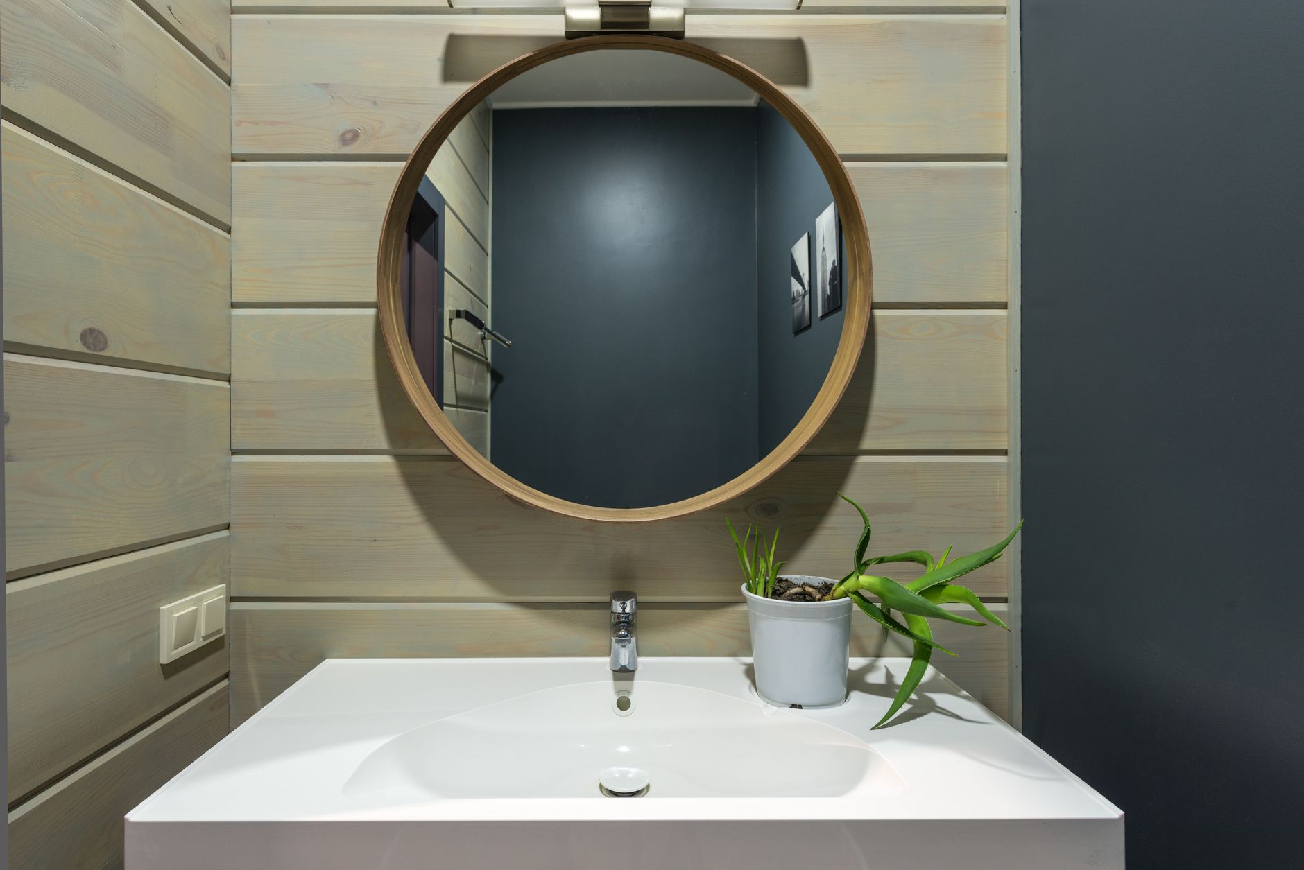 A compact bathroom made lighter with a round mirror and open vanity, showing how reflection can widen a tight room.