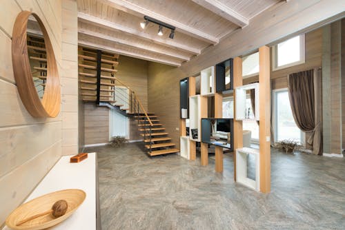 Entrance of cottage with stairway to second floor and geometric shelves separating corridor from living room