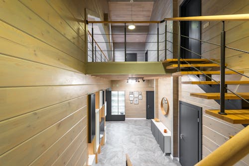 Interior of spacious house with stairway leading to entry with door and mirror handing above cupboards