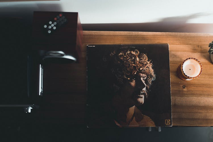 Top View Photography Of Vinyl Album Case Near White Tealight Candle Placed On Brown Table