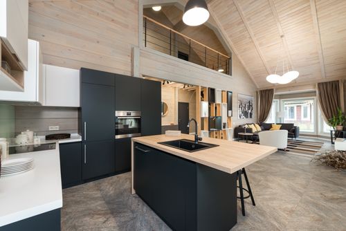 Free Stylish matte furniture and built in appliances under glowing lamp hanging on wooden ceiling with living zone in spacious house Stock Photo