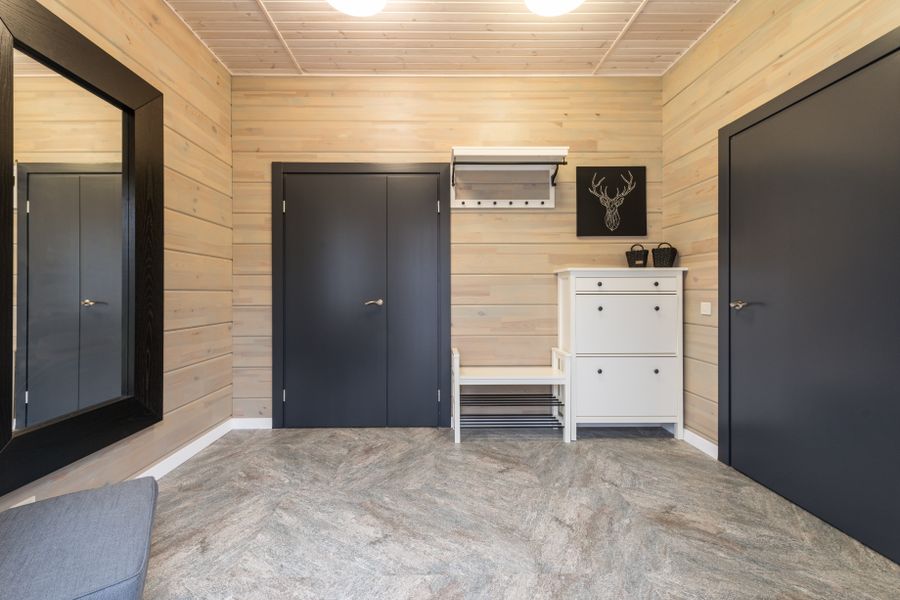 Spacious hallway with metal doors and shoe rack placed near cupboard under picture of deer handing on paneled wall