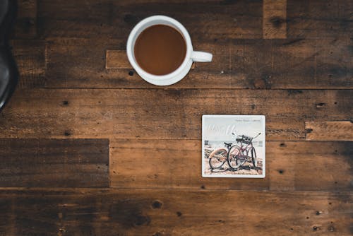 Белая керамическая кружка с кофе рядом с фотографией двух горных велосипедов