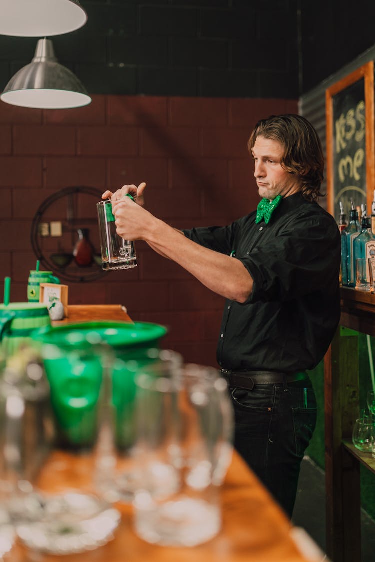 Man In Black Long Sleeves Mixing A Drink On A Pitcher