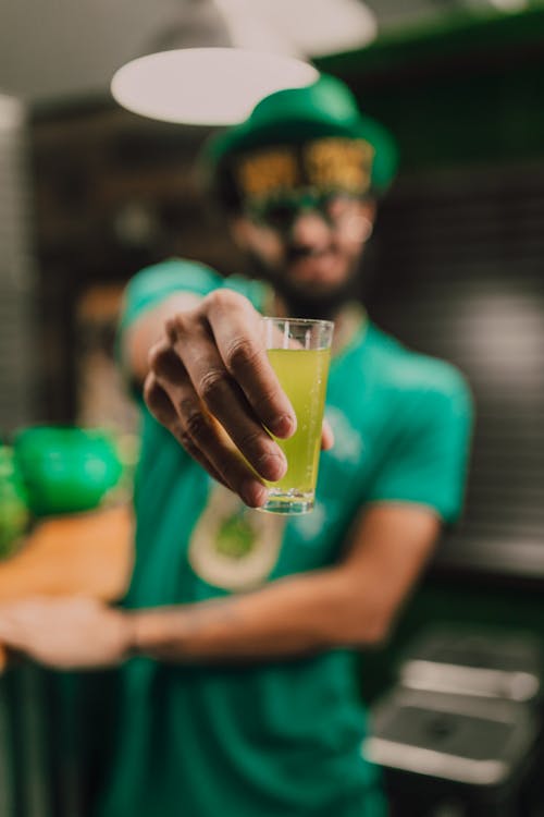 A Person in Green Shirt Holding a Shot Glass 