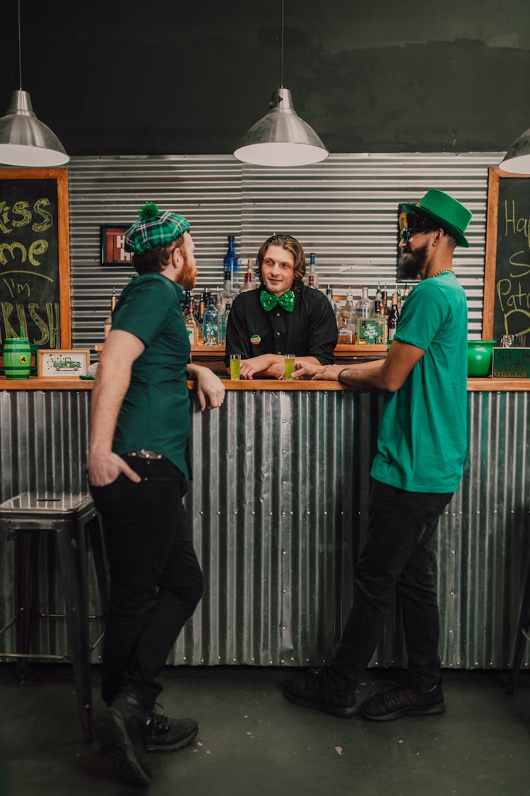 A Bartender And Two Men Talking Together 