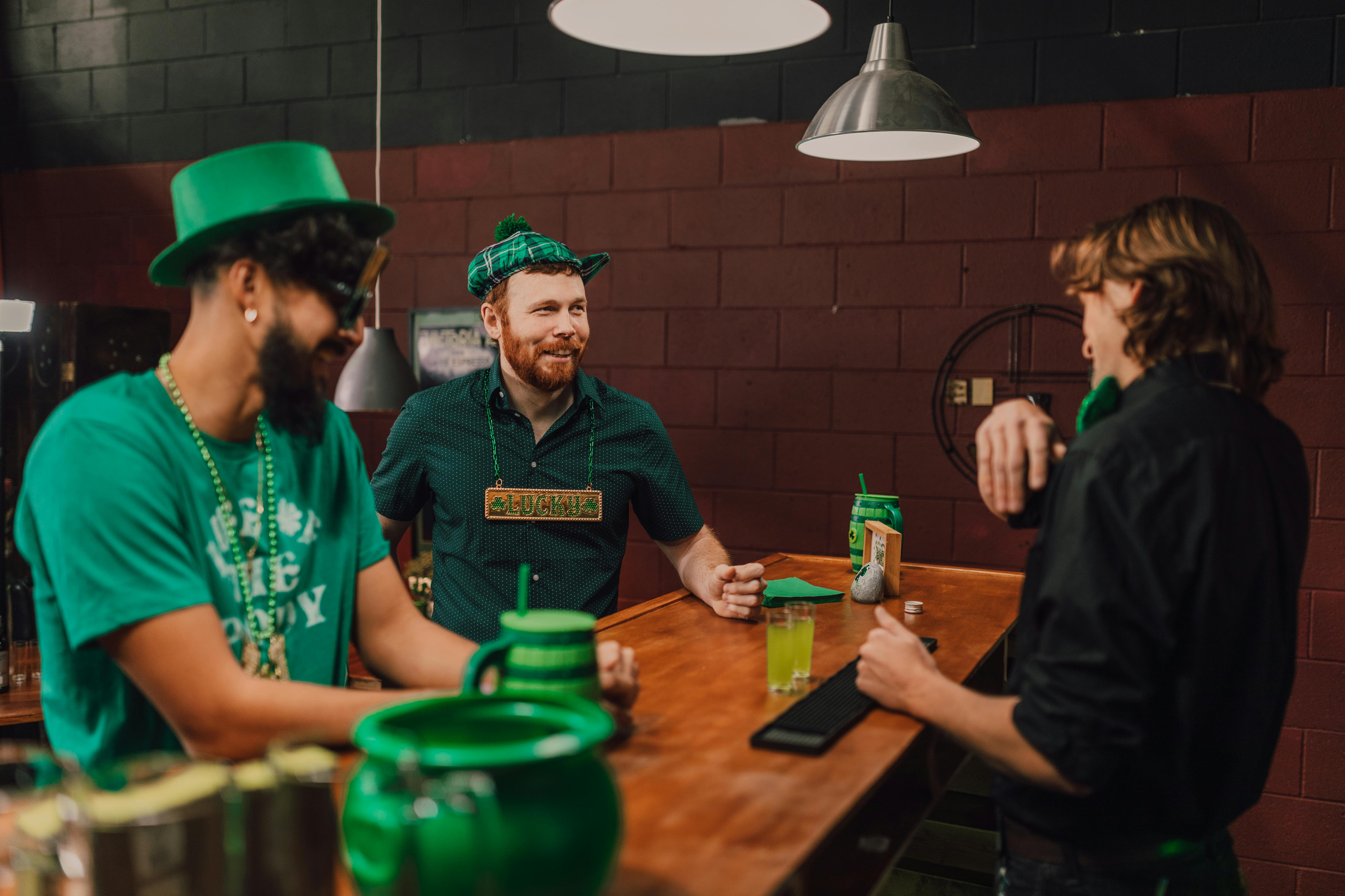 Three men enjoying St. Patrick's Day festivities at a bar, surrounded by green decor.