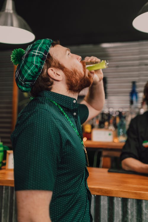 Man Wearing Green Clothes Drinking a Shot