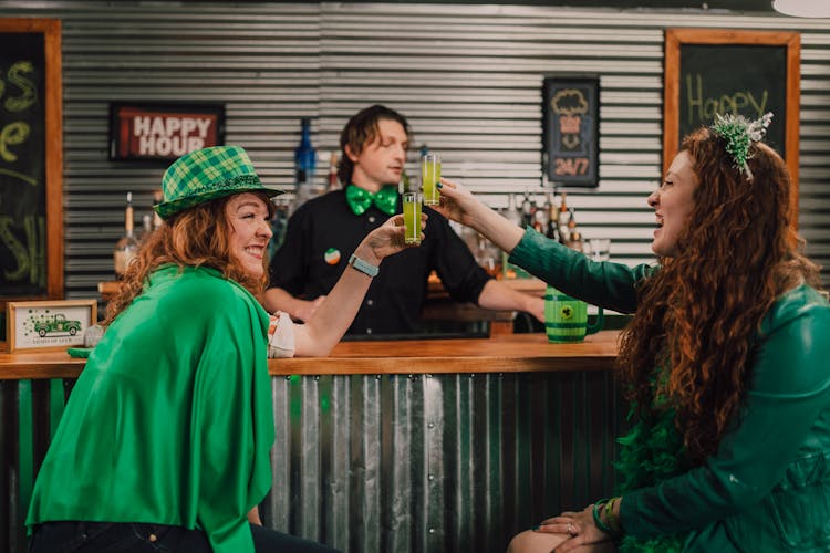 Two Women In Green Clothes Drinking Shots 