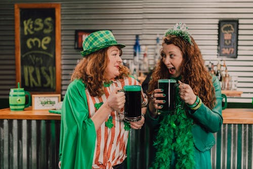 A Pair of Women Celebrating St Patrick's Day Holding Glasses of Beers