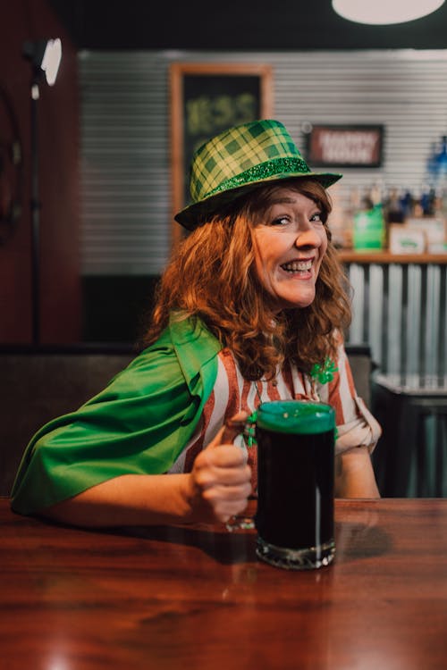 A Woman Wearing Green Hat Holding a Glass of Beer
