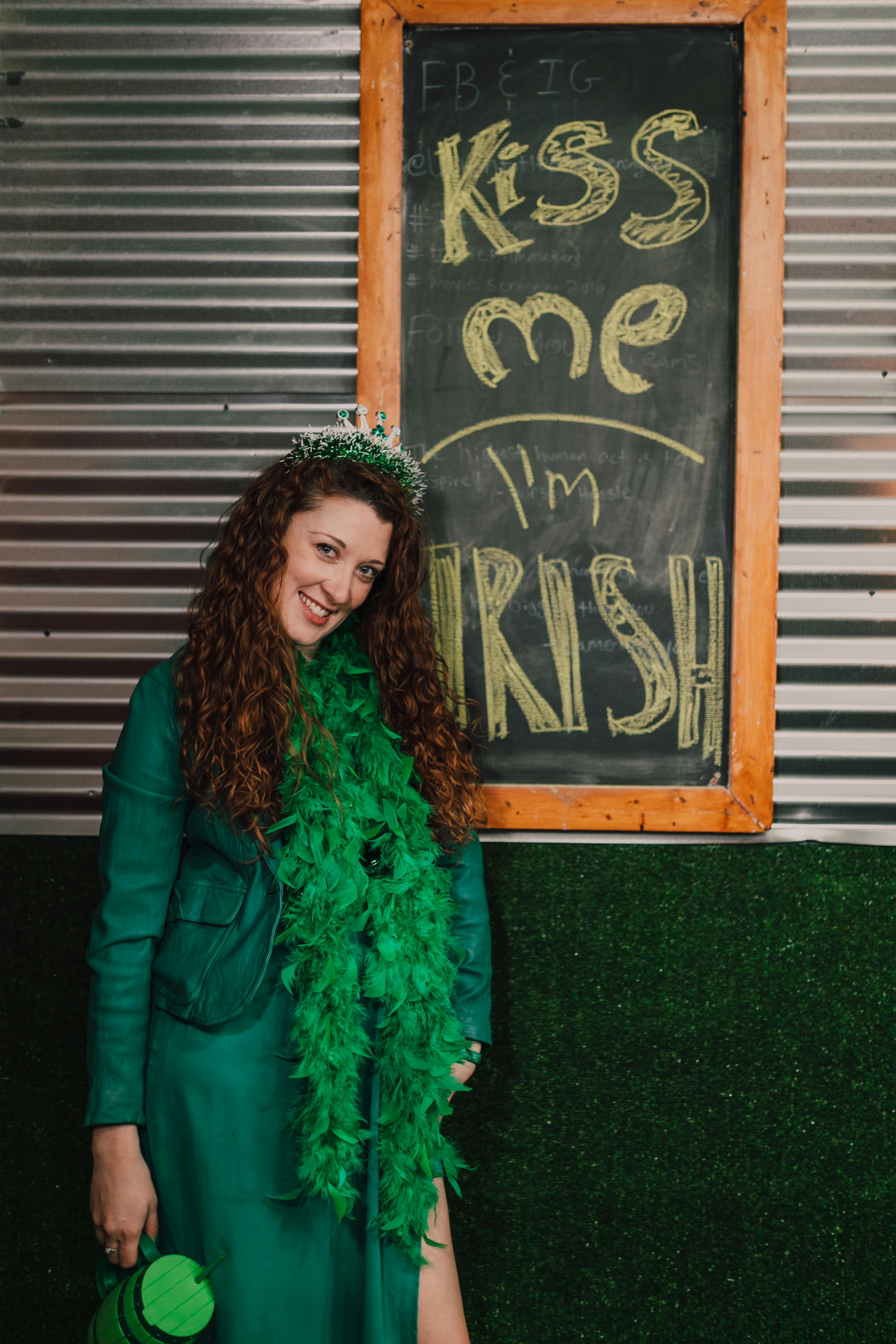 a happy woman in green dress standing beside a board with message while smiling at the camera