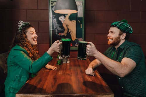 Man and Woman Sitting at Table Drinking Green Beer