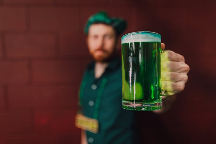 Close-up Of A Man Holding Green Juice On Clear Glass 