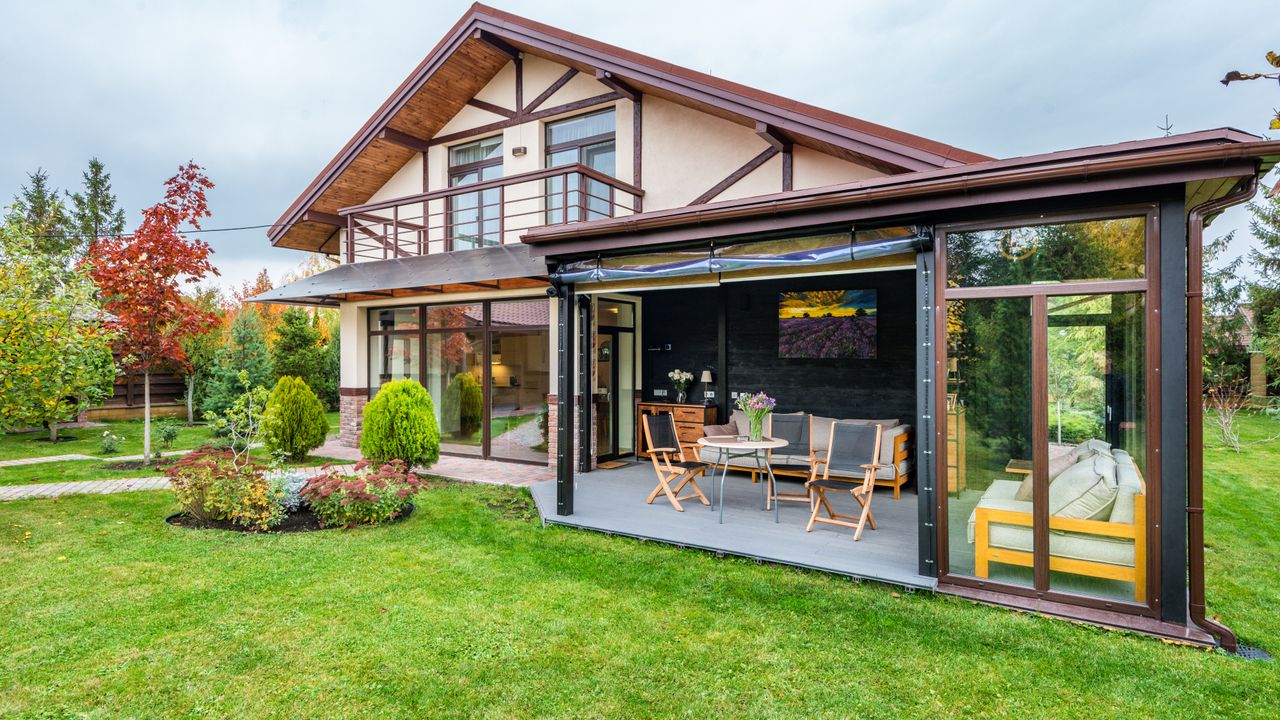 A house behind a wide cut lawn and a laid paver patio