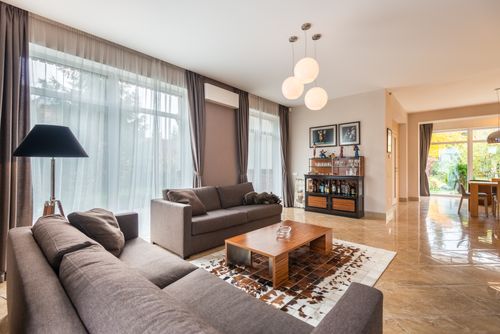 Free Interior of contemporary spacious living room with comfortable sofa and wooden table near windows with curtains Stock Photo