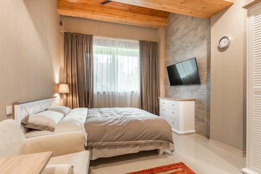 Elegant bedroom featuring comfortable bed, stylish decor, and natural daylight.