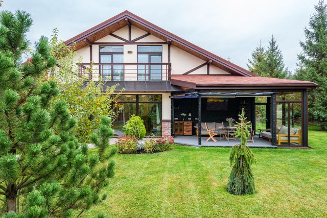 A contemporary house with a covered terrace and pine trees. Photo by Max Vakhtbovych on Pexels.