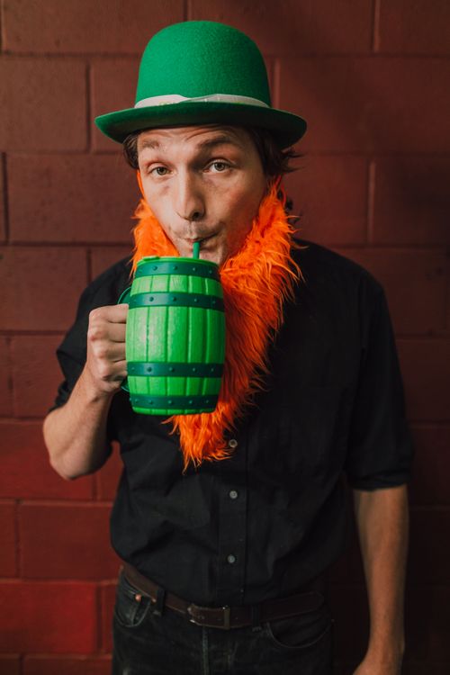 Free Man in green hat and orange beard drinking from a green mug, celebrating St. Patrick's Day. Stock Photo