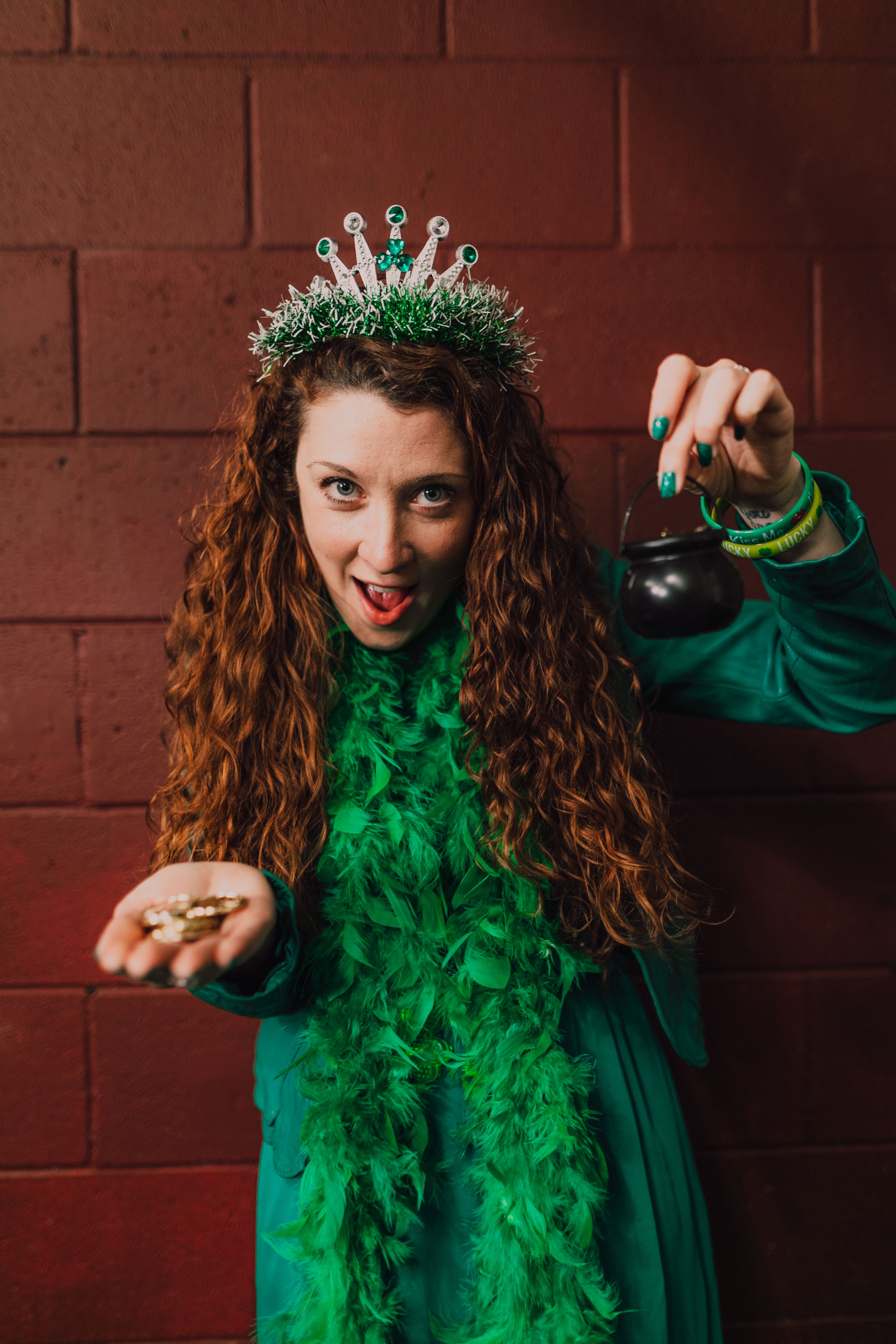 Woman in green costume holding pot of gold against red background for St. Patrick's Day.