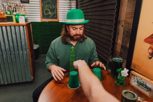 Free Man in a green hat and tie enjoying a St. Patrick's Day celebration indoors. Stock Photo